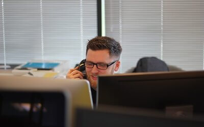 Imagen en la que aparece un hombre en una oficina atendiendo una llamada telefónica.